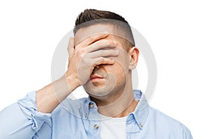 Unhappy man covering his eyes by hand