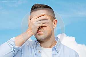 Unhappy man covering his eyes by hand