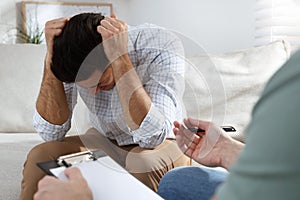 Unhappy man having session with his therapist indoors
