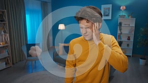 Unhappy man keeps his hand on his temple while suffering from an attack of headache, close up. A person feels bad from