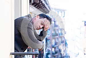 Unhappy man suffering from depression feeling desperate, and worthless on home balcony