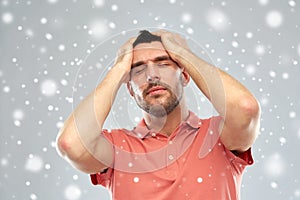 Unhappy man suffering from head ache over snow