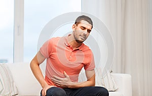 Unhappy man suffering from stomach ache at home