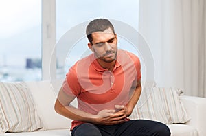 Unhappy man suffering from stomach ache at home