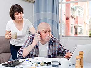 Unhappy man talking by phone, woman trying to help