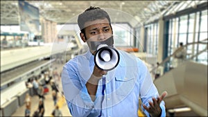 Unhappy man with taped mouth trying to speak in megaphone.