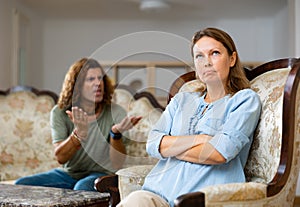 Unhappy married couple arguing among themselves while sitting on a Victorian sofa at home