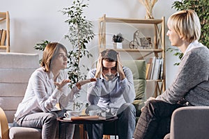 Unhappy married couple, sad, depressed man and woman meeting with doctor, psychologist to solve family problem.