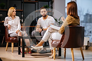 Unhappy married couple sit having conversation with psychologist