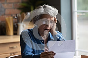 Unhappy senior woman shocked by bad news in postal correspondence photo