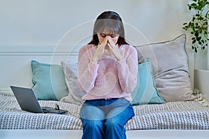 Unhappy mature woman experiencing headaches stress depression sitting on couch at home