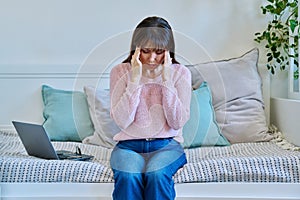 Unhappy mature woman experiencing headaches stress depression sitting on couch at home