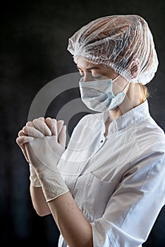 Unhappy medical female nurse in white uniform and praying  on black