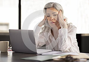 Unhappy Middle Aged Businesswoman Having Stress And Headache At Workplace