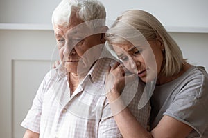 Unhappy middle-aged wife supporting and comforting older husband