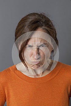 Unhappy middle aged woman grumbling and pouting, expressing anger