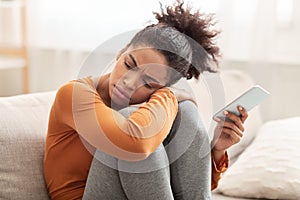 Unhappy Millennial Girl Holding Phone Sitting On Sofa At Home