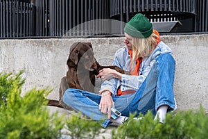 Unhappy millennial guy and cute homeless pet dog sitting together outdoors