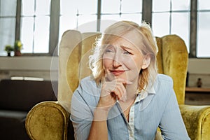 Unhappy misunderstood woman having weird face while sitting