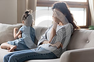 Unhappy mother touching forehead, feeling tired of bad daughter`s behavior.