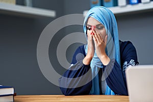 Unhappy muslim female student learning at home