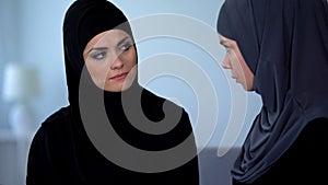 Unhappy muslim wife listening and sadly looking at friend, islamic obedience