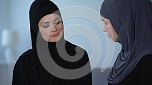 Unhappy muslim wife sigs sadly and looks at friend, islamic obedience, crisis