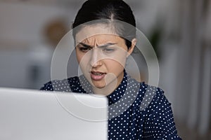 Unhappy nervous young Indian ethnicity woman looking at laptop screen.