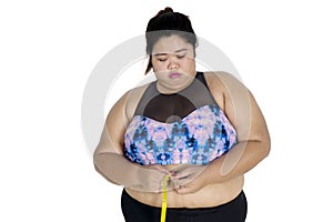 Unhappy obese woman measuring her tummy
