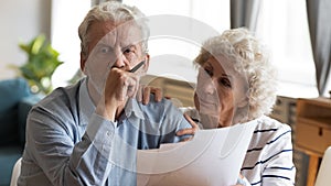 Unhappy older couple reading documents, checking domestic bills