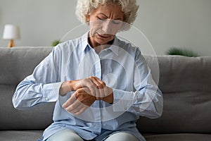 Unhappy older woman massaging wrist, feeling pain in joint