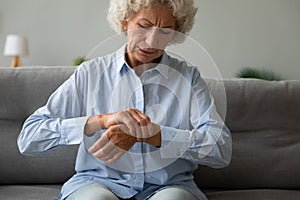 Unhappy older woman massaging wrist, feeling pain in joint photo