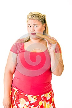 Unhappy overweight blond woman with raw carrot