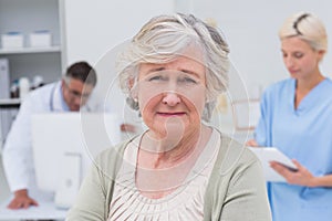 Unhappy patient with doctor and nurse working in background