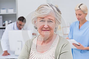 Unhappy patient with doctor and nurse working in background photo