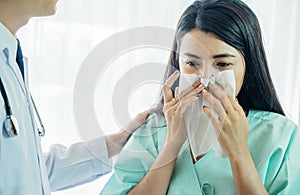 Unhappy patient using a tissue to sneeze and blowing her nose and get high fever from flu and cold