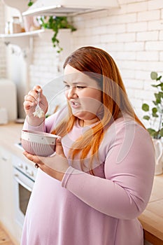 Unhappy plump woman looking at the oatmeal