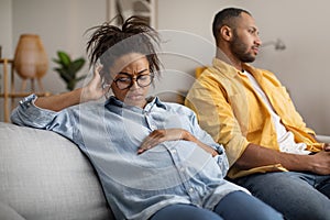 Unhappy Pregnant Black Wife Sitting Near Indifferent Husband At Home