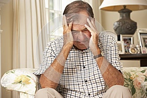 Unhappy Retired Senior Man Sitting On Sofa At Home