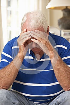 Unhappy Retired Senior Man Sitting On Sofa At Home