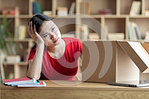 Unhappy sad disappointed teen girl sitting with cardboard box in living room interior