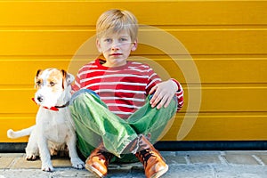 Unhappy sad preteen boy sitiing on the ground with his dog Jack Russell Terrier