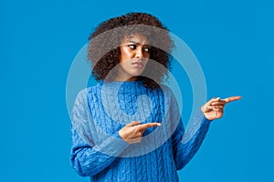 Unhappy sad and timid, insecure lovely african-american pretty woman with afro haircut in winter sweater, sighing uneasy