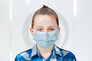 Unhappy, sad young boy wearing a protective face mask prevent virus infection or pollution