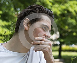 Unhappy, sad young man outdoors in park thinking