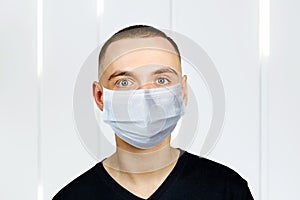 Unhappy, sad young man wearing a protective face mask prevent virus infection or pollution