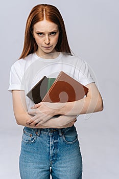 Unhappy sad young woman college student holding book and looking at camera on isolated background.