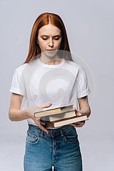 Unhappy sad young woman college student wearing T-shirt and denim pants holding book