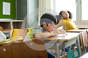 Unhappy Schoolboy studying in classroom at school during lesson, bored and discouraged student. School children education habit