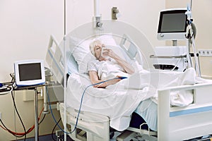 Unhappy senior lady with oxygen mask at hospital